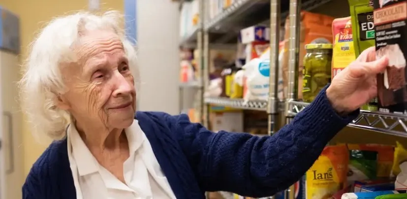 woman picking food item from pantry shelf