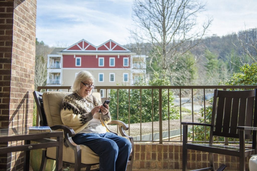 Senior woman smiling while using smartphone outdoors