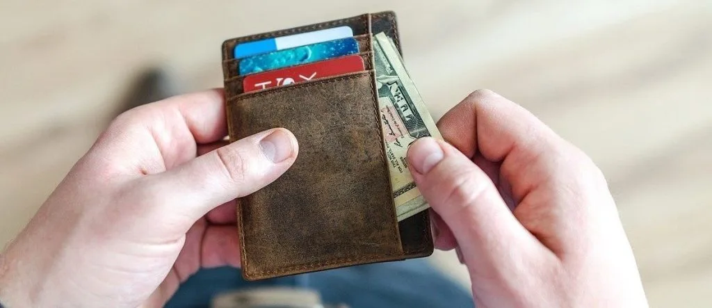 Person holding wallet with cash and credit cards