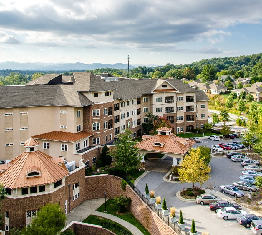 Large residential building with parking lot and greenery