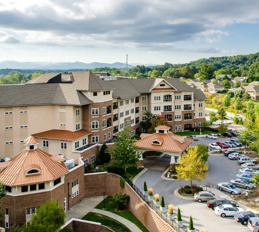 Large residential building with parking lot and greenery